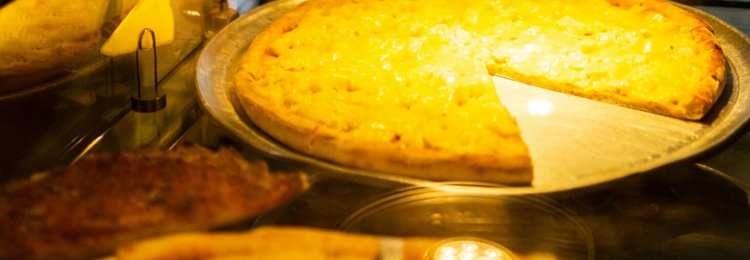 A woman looks at delicious pizza options in a cozy São Paulo restaurant.